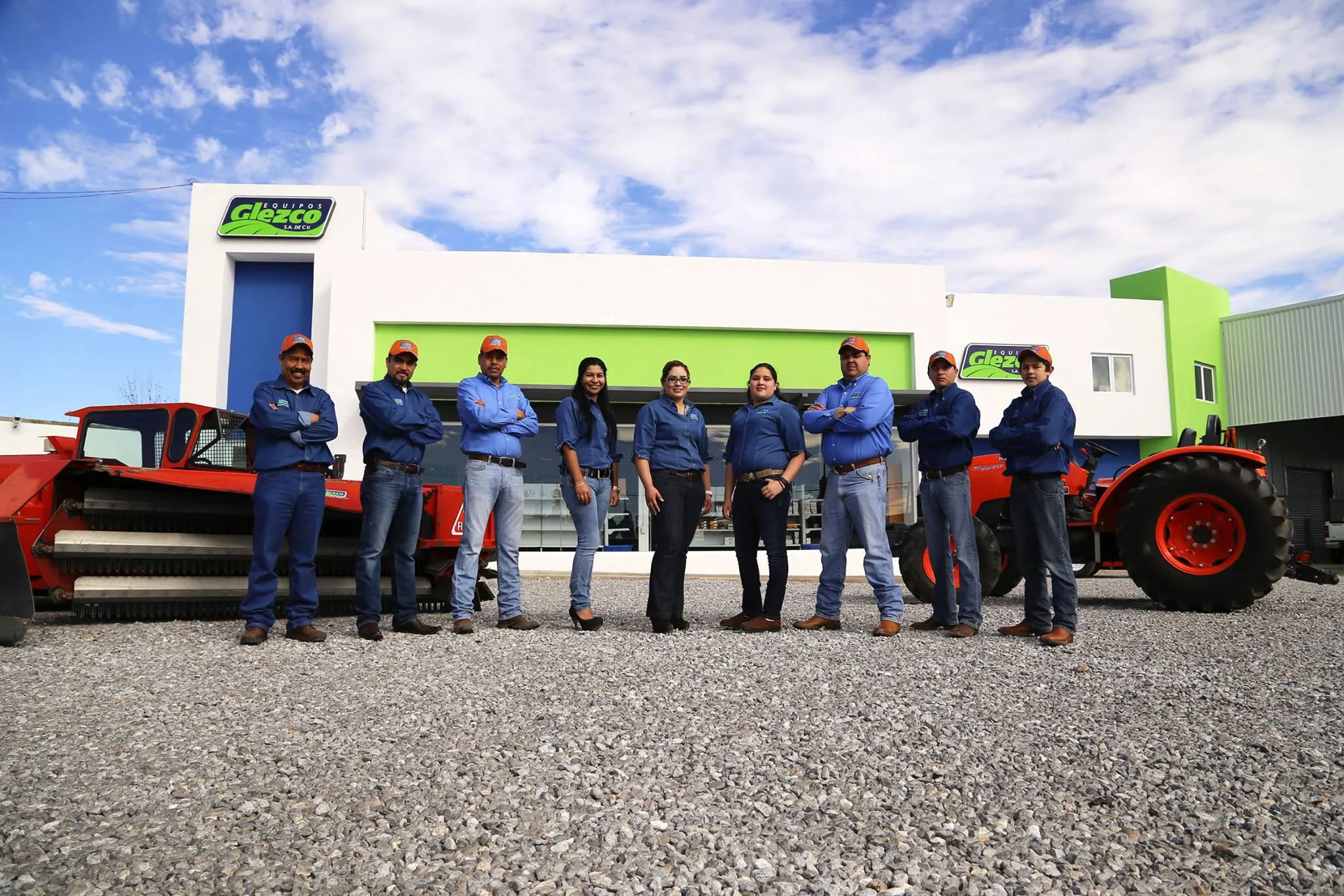 Equipo de Equipos Glezco frente a sus instalaciones, con maquinaria agrícola